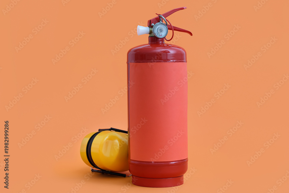 Naklejka premium Fire extinguisher and hearing protectors on orange background