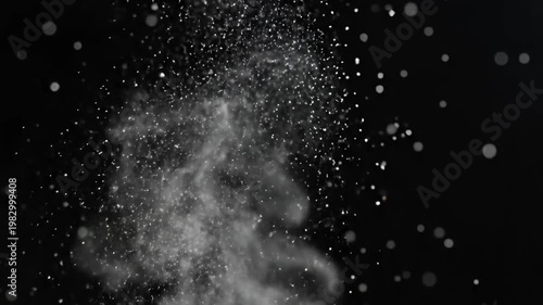 White particles scattering upwards on a dark black background