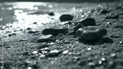 Monochrome shot of wet stones on beach with shallow depth of field, water reflection, nature and seascape creating peaceful mood.