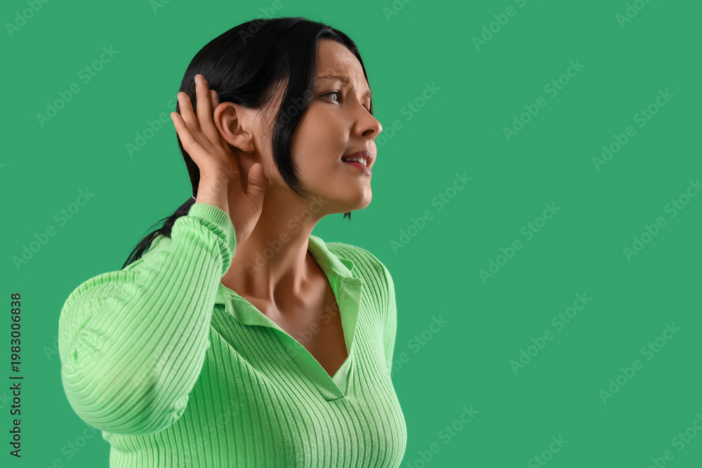 Fototapeta premium Young woman trying to hear something on green background, closeup