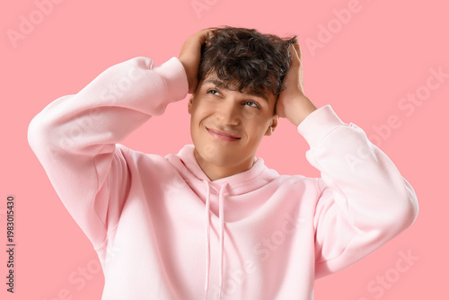 Portrait of handsome young man scratching his head on pink background