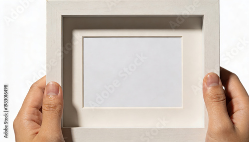 Human hand gently holds white empty picture frame with blank mat, ready for cherished photo or art display. Feeling of expectation and possibility