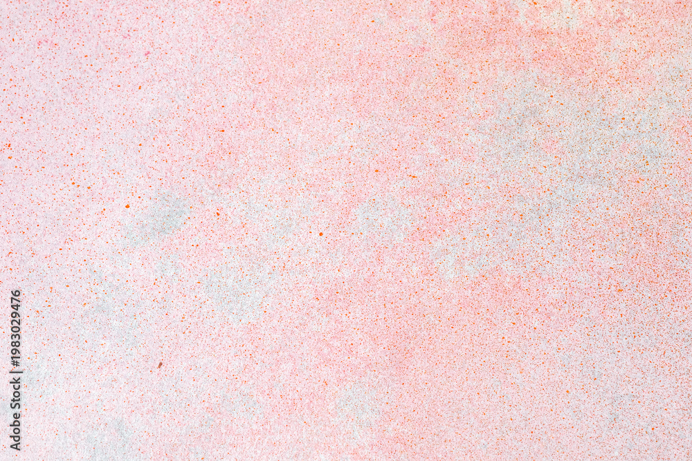 Fototapeta premium Vibrant textured surface of a light pink wall showing distressed paint and fine colorful speckles