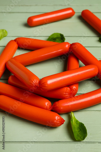 Tasty thin sausages and spinach on green wooden background