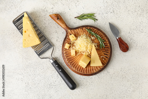 Wooden board with tasty Swiss cheese on light background