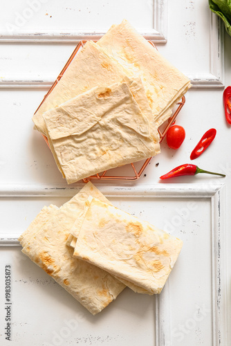 Grid with fresh lavash on white wooden background