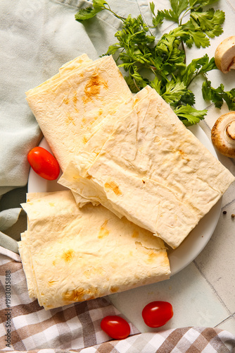 Plate with fresh lavash on white tile background