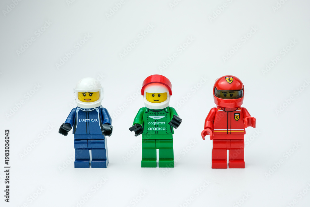 Fototapeta premium Three Lego racing minifigures in blue, green, and red outfits standing in a row on a white background. Suitable for Lego toys, racing, and minifigures on Apr 13, 2026 in Jakarta, Indonesia