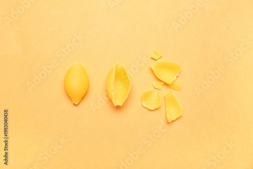 Raw conchiglie pasta on yellow background