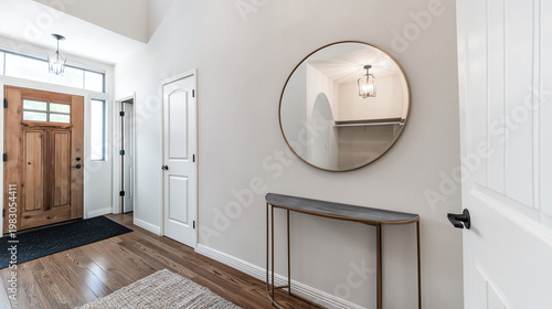 Hallway interior showcases a minimalist metal console table paired with a large circular mirror reflecting the elegant architecture of a modern home.