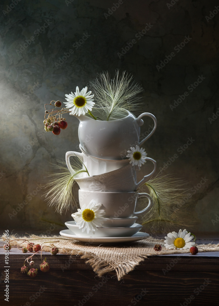Fototapeta premium Still life with porcelain dishes, daisies and berries on a dark background