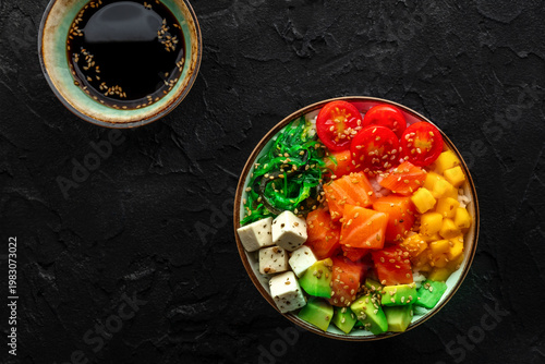 Salmon poke bowl with mango, avocado, tofu, wakame, overhead shot