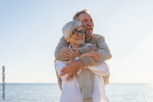 Senior mature couple hugging enjoying outdoor recreation walking on beach. Old husband wife embracing with tenderness love enjoying sweet bonding. Grandmother grandfather together. Family moment love