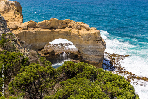 Dramatic cliffs soar over turquoise waters and waves crash beneath the rock formation The Arch along the Great Ocean Road, offering breathtaking views.