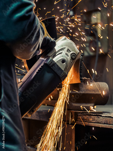 Fotografi A worker uses an angle grinder to cut metal, producing vivid sparks
