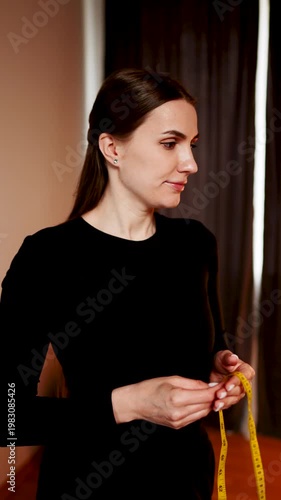 Woman measures body parts in front of mirror using measuring tape in indoor space