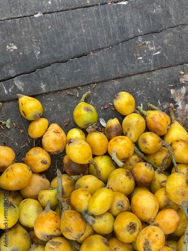 Fresh loquats piled on weathered wooden planks in rustic setting