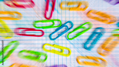 Clips de colores variados sobre una libreta con hojas cuadriculadas.