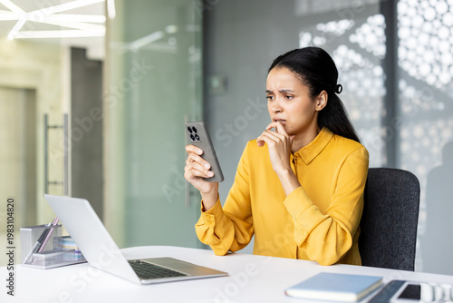 Billede på lærred Concerned young businesswoman sitting at her office desk, looking stressed and a