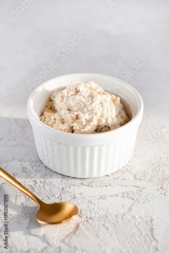 Vegan cashew ricotta in a bowl with golden spoon. Healthy plant based breakfast. Sugar, lactose and gluten free. Vertical orientation.