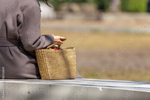 Φωτογραφία Woman sitting on park bench in dappled light, focused on smartphone