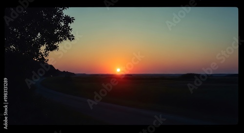 A serene sunset over a vast landscape with a tree silhouette