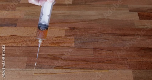 Laminated wood board finished with tung oil dispensed from a syringe