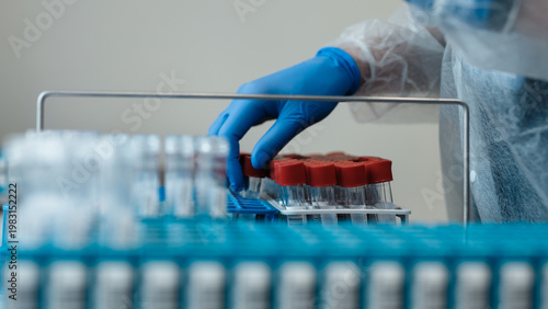 Canvastavla Laboratory technician in protective gear handling blood sample vials with red ca