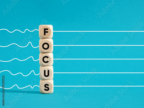 Wooden blocks with the word focus aligning clear path on blue background
