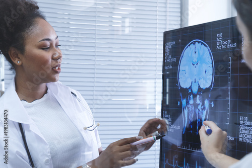 Young diverse female doctor students looking at MRI and CT scans on monitor in hospital office. radiologists meeting to discussing patient cancer surgery at lab. healthcare and medical education.