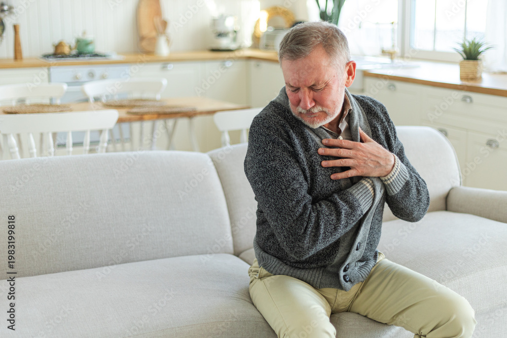 Fototapeta premium Pain on heart, heart attack. Unhappy middle aged senior man suffering from chest pain heart attack problems with health at home. Mature old senior grandfather touching chest experiencing infarction