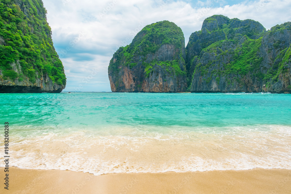 Obraz premium Tropical Maya bay beach with turquoise water, white sand and limestone cliffs on Phi Phi islands, Krabi, Thailand with nobody. Empty beach with rocks and lush greenery. Travel and tourism in Asia