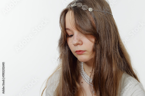 Portrait of a pensive young girl wearing pearl jewelry.