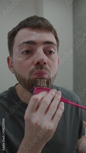 White man detailing beard tint with small brush and precise strokes along edges, concentrated care for uniform shade, mirror check