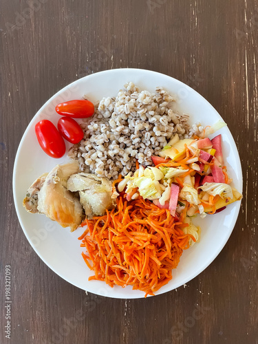 Top view of plate with balanced meal of pearl barley, carrot and cabbage apple salads, baked chicken and cherry tomatoes, healthy eating and nutrition