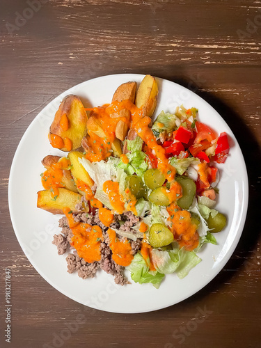 Top view of plate with balanced burger bowl of baked potato, ground meat, fresh greens, pickles, tomato sauce and cheese, healthy eating and nutrition