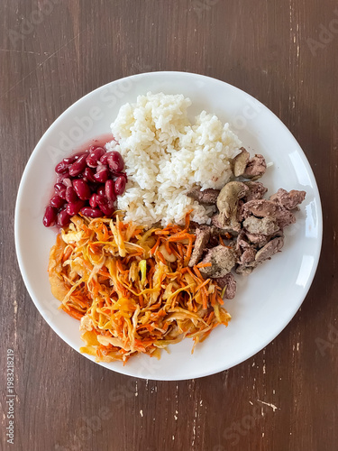 Top view of plate with balanced meal of rice, chicken liver, carrot salad and red beans, healthy eating and nutrition