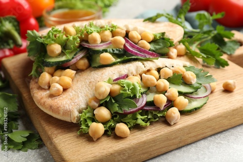 Pieces of pita bread with chickpeas and vegetables served on light grey table, closeup