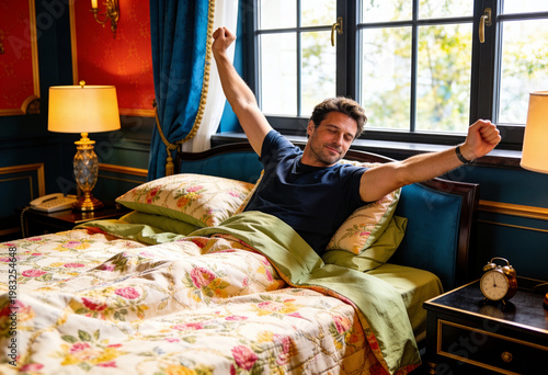 Man stretching arms after waking up in bedroom