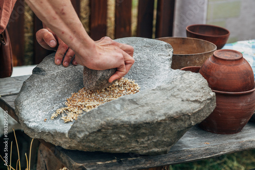Fotografija Human hand rotating an ancient stone grinding machine for smashing grains