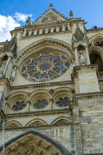 The sun illuminates the intricate stonework of this historical French masterpiece. Intricate rose windows and majestic stone statues define the facade of this cathedral.