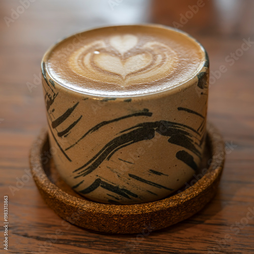 A modern coffee mug, containing a Flat white, with an intricate design on the top, served in a coffee shop on the Island of Java, Indonesia