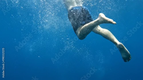 Person swimming underwater with bubbles in deep blue ocean