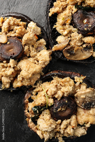 Stuffed roasted fried large portobello mushroom minced chicken on black slate background closeup details