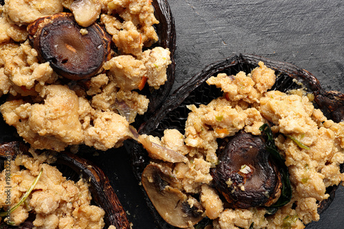 Stuffed roasted fried large portobello mushroom minced chicken on black slate background closeup details
