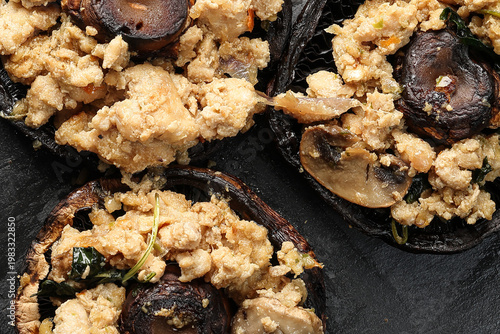 Stuffed roasted fried large portobello mushroom minced chicken on black slate background closeup details