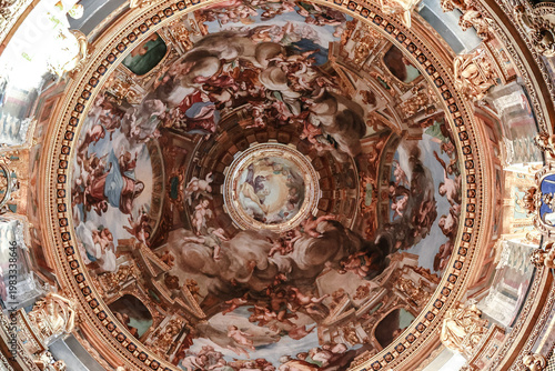 Detailed painted ceiling with religious figures and rich ornamentation creating dramatic sacred atmosphere in historic church interior Genoa, Italy