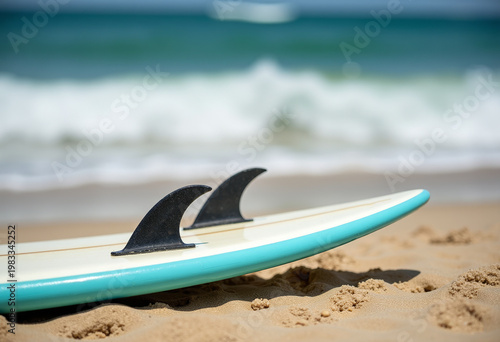 Surfboard lay on sand with ocean waves in background