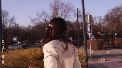 Close-up of young brunette woman in stylish sunglasses walking on city street on sunny day. Perfect for lifestyle, fashion, urban and travel themed commercial projects