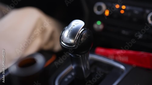 Close-up of woman hand with ring shifting automatic transmission gear selector to drive mode in car. Perfect for automotive, driving and transportation themed commercial projects